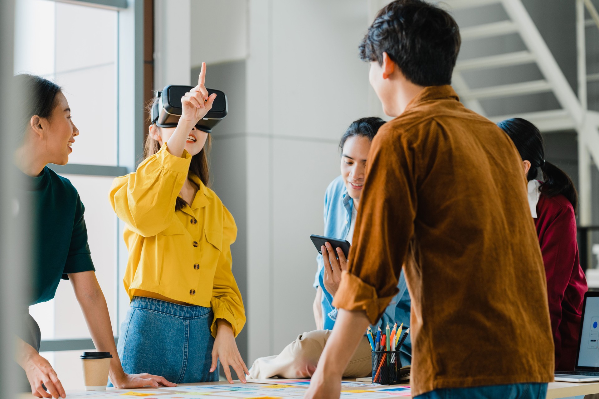 Empresários asiáticos e empresárias que se reúnem com ideias de brainstorming usando óculos de realidade virtual (realidade virtual) testando aplicativo móvel a partir do desenvolvimento de software trabalhando juntos em escritórios modernos.
